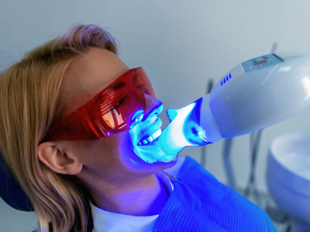 woman getting professional teeth whitening treatment at the dentist