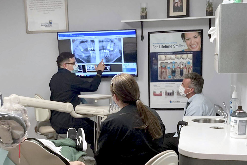 Dentist points at x-ray on screen to show patient's results